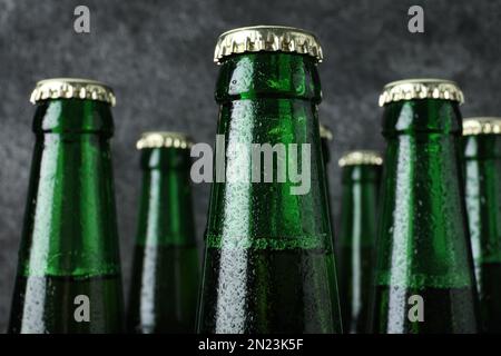 Flaschen Bier auf grauem Hintergrund, Nahaufnahme Stockfoto