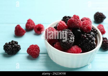 Leckere gefrorene Brombeeren und Himbeeren auf einem hellblauen Holztisch. Platz für Text Stockfoto
