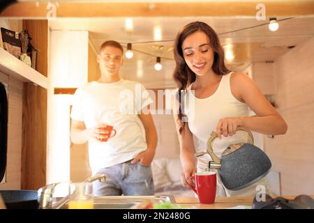 Glückliches junges Paar, das im Wohnwagen frühstückt. Campingurlaub Stockfoto