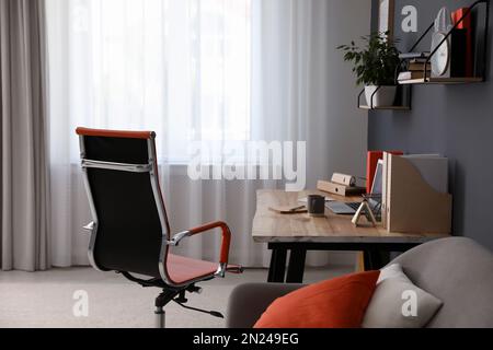 Moderner Arbeitsplatz mit komfortablem Stuhl in elegantem Innenraum des Heimbüros Stockfoto