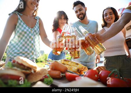 Fröhliche Freunde, die draußen mit Bierflaschen anstoßen. Campingsaison Stockfoto