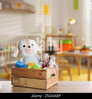 Set mit verschiedenen niedlichen Spielzeugen auf Holztisch im Kinderzimmer Stockfoto