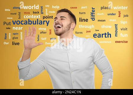 Glücklicher junger Mann, umgeben von einer Wortwolke auf gelbem Hintergrund Stockfoto