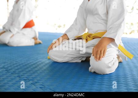 Kinder in Kimono sitzen auf Tatami, Nahaufnahme. Karate-Praxis Stockfoto