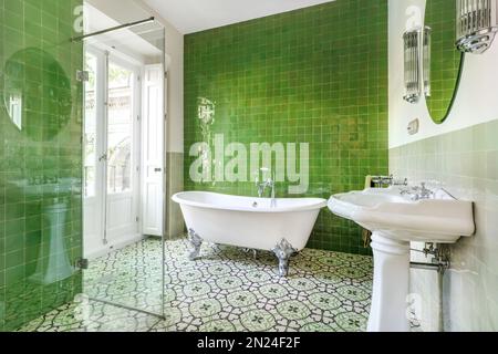 Schönes Badezimmer im Vintage-Stil mit Badewanne mit Klauen, Fliesen auf dem Boden und grünen Wänden Stockfoto