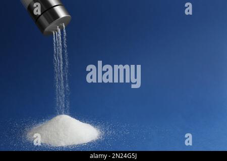 Salz wird aus dem Schüttler auf blauem Hintergrund gegossen. Platz für Text Stockfoto