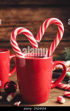 Eine Tasse heiße Schokolade mit Zuckerstangen auf einem Holztisch Stockfoto