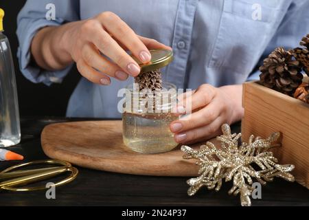 Frau, die Schneekugel am schwarzen Holztisch macht, Nahaufnahme Stockfoto