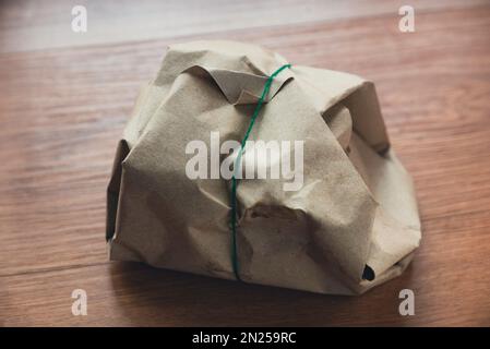 Reis mit mehreren Seitenschalen, braunes Ölpapier und Gummiband auf Holzhintergrund. Stockfoto