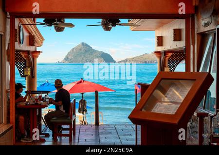 Gäste genießen ein Mittagessen mit Blick in einem Resort Café am Meer entlang des Sandstrands Playa Gaviotas in der Golden Zone von Mazatlan, Mexiko. Stockfoto