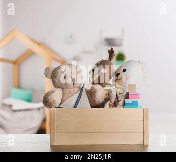 Set mit verschiedenen niedlichen Spielzeugen auf Holztisch im Kinderzimmer Stockfoto