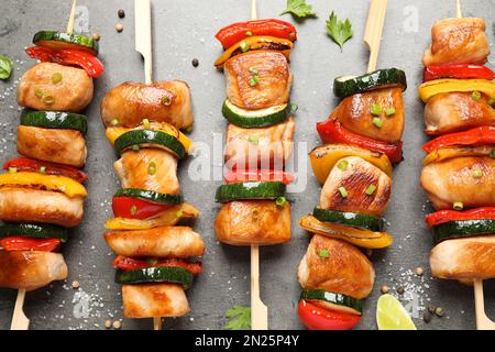 Köstliche Hähnchen-Shish-Kebabs mit Gemüse und Kräutern auf grauem Tisch, flach liegend Stockfoto