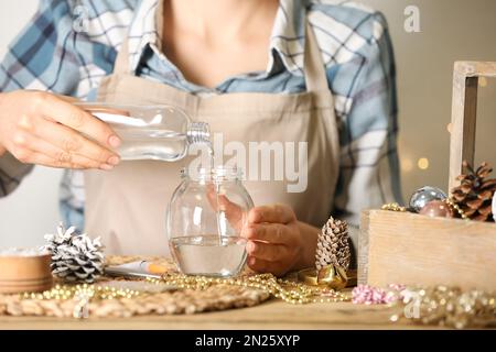 Frau, die Schneekugel am Holztisch macht, Nahaufnahme Stockfoto