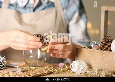 Frau, die Schneekugel am Holztisch macht, Nahaufnahme Stockfoto