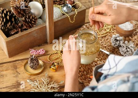 Frau, die Schneekugel am Holztisch macht, Nahaufnahme Stockfoto