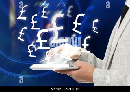 Geldwechselkonzept. Geschäftsmann mit Tablet-PC auf blauem Hintergrund, Nahaufnahme. Pfund Währungssymbole über dem Gerät Stockfoto