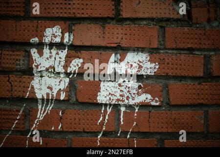 Handabdruckfarbe. Abdruck an der Ziegelwand. Weiße Silhouette der Handfläche. Fingerabdrücke an der Wand. Stockfoto