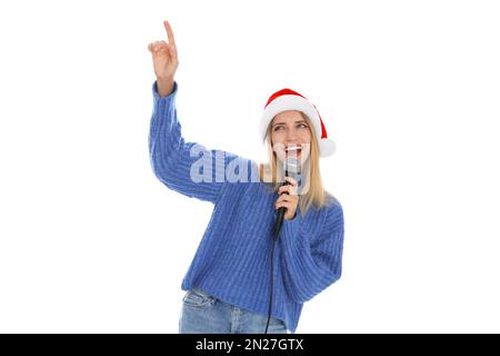 Glückliche Frau mit Weihnachtsmann-Hut, die mit Mikrofon auf weißem Hintergrund singt. Weihnachtsmusik Stockfoto