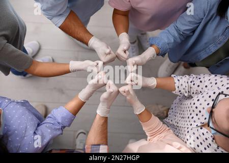 Gruppe von Menschen in weißen medizinischen Handschuhen, die drinnen Daumen nach oben zeigen, Draufsicht Stockfoto