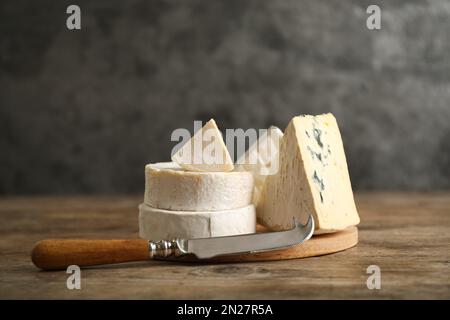 Verschiedene Käsesorten und Messer auf Holztisch Stockfoto