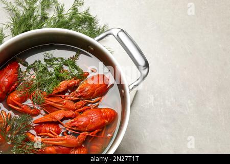 Frische köstliche Flusskrebse im Topf auf hellgrauem Tisch, flach liegend. Platz für Text Stockfoto