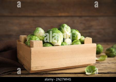 Kiste mit frischem Rosenkohl auf Holztisch, Nahaufnahme Stockfoto