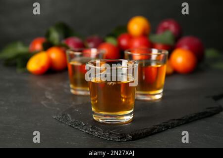 Köstlicher Pflaumenlikör auf schwarzem Tisch. Hausgemachtes, starkes alkoholisches Getränk Stockfoto