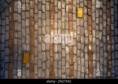 Fliesen an der Wand. Mosaikfliesen. Muster aus Scherben von farbigem Stein. Textur der Stücke. Stockfoto