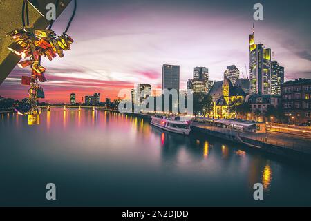 Blick über den Main bis zur Sonnenuntergang-Skyline von Frankfurt am Main, Abend, Liebesschlösser, Sonnenuntergang mit Hintergrundbeleuchtung, Hessen, Deutschland Stockfoto