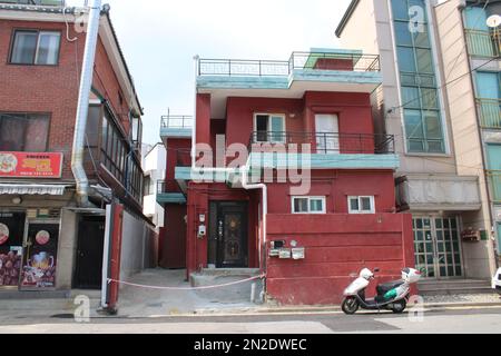 Rotes Backsteingebäude im Villenstil mit weißem Roller vorne Stockfoto