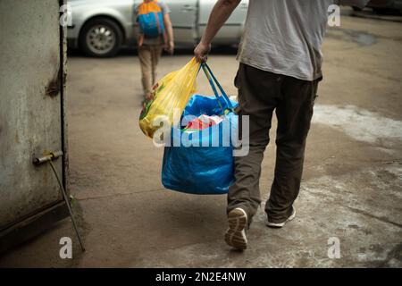 Mann mit blauer Tasche. Sich mit Dingen zu bewegen. Ein Typ, der Sachen zieht. Eine Person schießt im Auto. Stockfoto