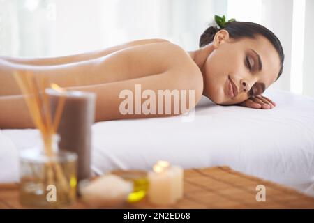 Der perfekte Tag... Eine junge Frau, die in einem gesundheitssack liegt, umgeben von Duftkerzen. Stockfoto