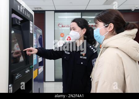 ZHOUSHAN, CHINA - 7. FEBRUAR 2023 - Polizei vom Exit and Entry Administration Bureau des Public Security Bureau leitet Bewerber zur Verwendung von Self-s Stockfoto