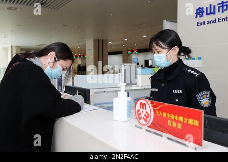 ZHOUSHAN, CHINA - 7. FEBRUAR 2023 - Ein Mitarbeiter des Exit and Entry Administration Bureau des Public Security Bureau beantwortet die antwort eines Antragstellers Stockfoto