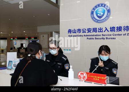ZHOUSHAN, CHINA - 7. FEBRUAR 2023 - Ein Mitarbeiter des Exit and Entry Administration Bureau des Public Security Bureau beantwortet die antwort eines Antragstellers Stockfoto