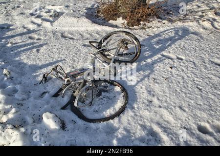 Ein kaputtes Fahrrad lag im Schnee Stockfoto