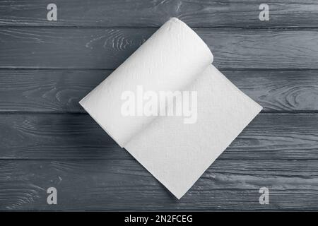 Rolle mit Papiertüchern auf grauem Holztisch, Draufsicht Stockfoto