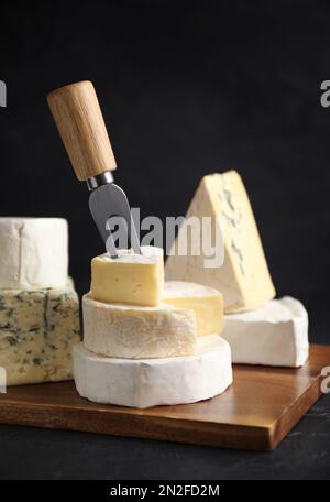 Verschiedene Käsesorten und Gabel auf schwarzem Tisch Stockfoto