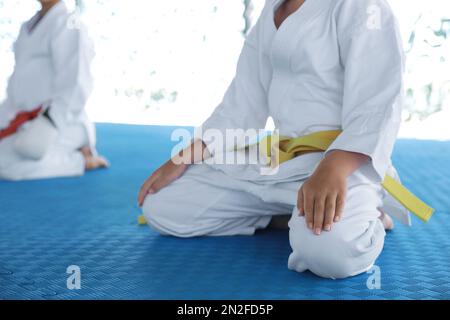 Kinder in Kimono sitzen auf Tatami, Nahaufnahme. Karate-Praxis Stockfoto