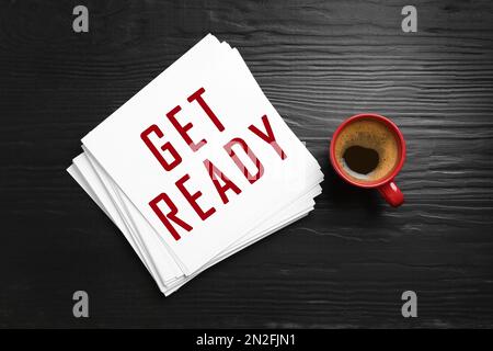 Karte mit Text „Get Ready“ und einer Tasse Kaffee auf einem dunklen Holztisch, flach liegend Stockfoto