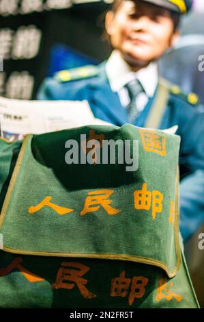 Ausstellung eines Postboten mit der Tasche mit der Aufschrift „China People’s Post Office“ im Postmuseum am Nordufer von Suzhou Cr Stockfoto