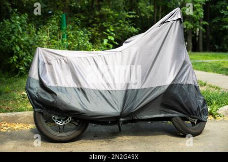 Fahrrad im Hof. Transport abdecken. Motorrad im Etui. Motorrad auf dem Parkplatz. Regenfeste Markise, Stockfoto