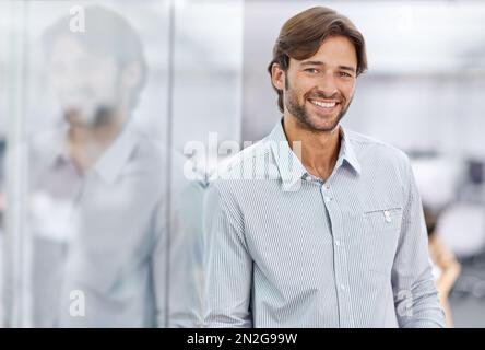 HES ein selbstbewusster junger Geschäftsmann. Porträt eines hübschen jungen Geschäftsmannes, der in seinem Büro steht. Stockfoto
