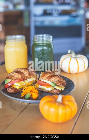 Croissant gefüllt mit Avocado, Tomaten und Ei, frische Säfte und Kaffee auf dem Tisch in einem Restaurant Stockfoto