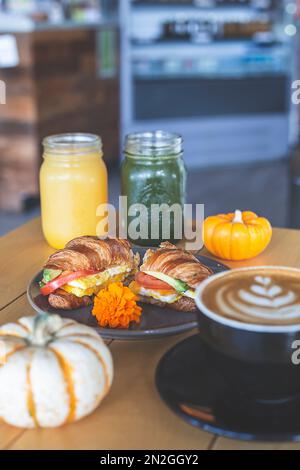 Croissant gefüllt mit Avocado, Tomaten und Ei, frische Säfte und Kaffee auf dem Tisch in einem Restaurant Stockfoto