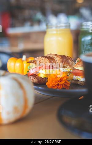 Croissant gefüllt mit Avocado, Tomaten und Ei, frische Säfte und Kaffee auf dem Tisch in einem Restaurant Stockfoto