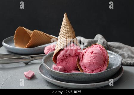 Köstliches rosa Eis in Waffel serviert auf grauem Tisch Stockfoto