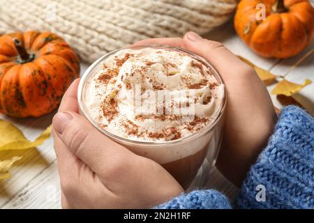 Eine Frau mit leckerem Kürbis-Latte am weißen Tisch, Nahaufnahme Stockfoto