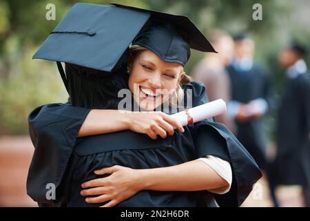 Wir haben endlich unseren Abschluss gemacht. Zwei College-Absolventen umarmen sich in Herzlichen Glückwunsch. Stockfoto