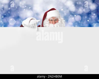 Weihnachtsmann mit leerem Banner auf unscharfem blauem Hintergrund. Raum für Design Stockfoto
